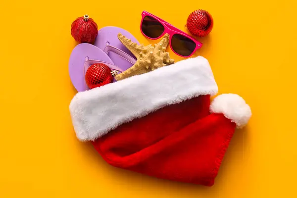 彩色背景的圣诞礼帽 圣诞球和海滩饰物的构图 免版税图库照片