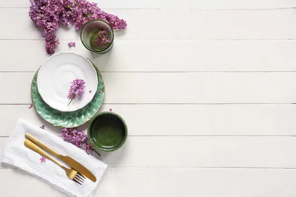 漂亮的餐桌布置 白木背景上有紫丁香花 免版税图库图片