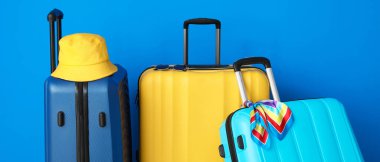 Mavi arka planda bavullar ve plaj aksesuarları. Seyahat kavramı