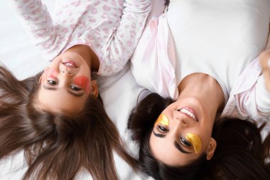 Mutlu anne ve göz altı bantlı küçük kızı yatağında uzanmış, yukarıdan.