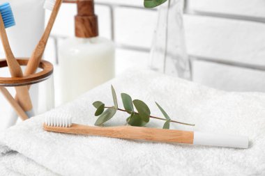 Diş fırçası ve okaliptüs dalı temiz havluda, yakın plan.