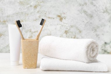 Bambu diş fırçalı tutucu, temiz havlu ve arka planda yapıştırıcı.