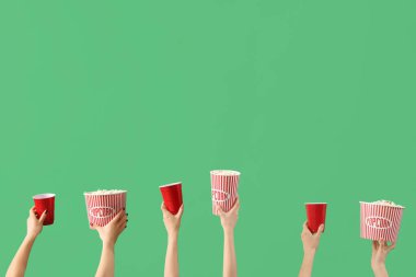 Patlamış mısırlı kovaları tutan eller ve yeşil arka planda içkiler