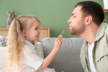 Evde babasına makyaj yapan sevimli küçük bir kız.