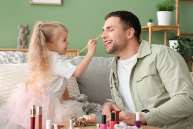 Evde mutlu babasına makyaj yapan sevimli küçük kız.