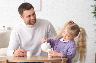 Mutlu bir baba ve tatlı küçük kızı evde çay partisi veriyorlar.