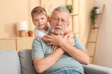 Büyükbaba ve küçük tatlı torunu evdeki kanepede oturuyor.
