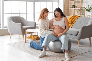Evde doula ile fitbol oynayan hamile bir kadın.