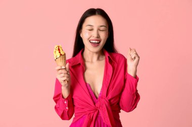 Güzel mutlu Asyalı kadın pembe arka planda mangolu dondurma