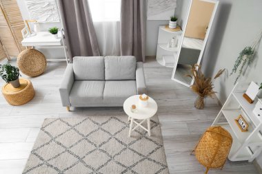 Gri kanepesi, sehpası ve halısı olan açık renkli oturma odası.