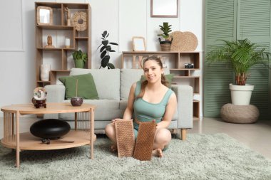 Sadhu tahtası olan genç bir kadın evde halının üzerinde oturuyor.