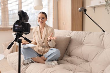 Dizüstü bilgisayarlı genç bir kadın evdeki podcast 'i kaydediyor.