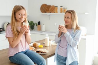 Mutlu anne ve kızı evde bir bardak sütle