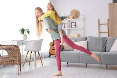 Küçük kızıyla evde yoga yapan sportif bir kadın.