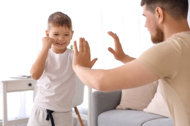 Genç adam ve küçük oğlu oturma odasında boks yapıyor.