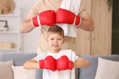 Oturma odasında boks eldivenli küçük oğlu olan genç bir adam.