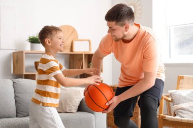 Genç adam ve küçük oğlu evde basketbol oynuyorlar.