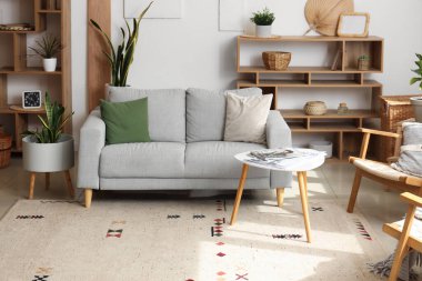 Kanepe, raf üniteleri ve beyaz duvarın yanındaki ev bitkilerinin olduğu rahat bir oturma odası.