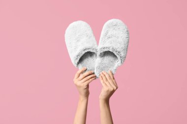 Pembe arka planda pofuduk gri terlikleri tutan kadın elleri