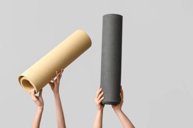 Gri arkaplanda yoga minderleri olan kadın elleri.