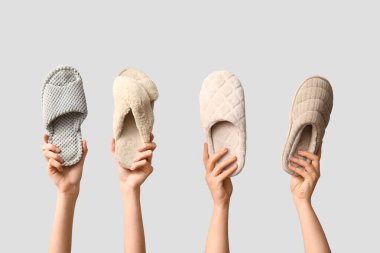 Beyaz arka planda terlikleri tutan kadın eller.