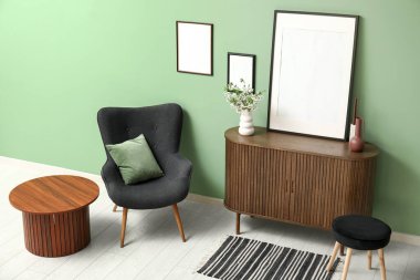 Boş çerçeve ve çiçek açan dallar yeşil duvarın yanındaki ahşap çekmece sandığında.