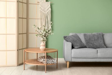 Masadaki vazoda güzel dallar, katlanan ekran ve oturma odasındaki rahat kanepe.