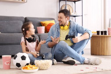 Küçük kızı evde video oyunu oynarken mutlu bir baba.