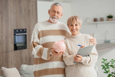 Mutfakta kumbarası ve panosu olan olgun bir çift.