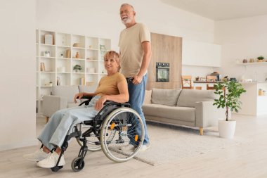 Kocasıyla birlikte tekerlekli sandalyede oturan olgun bir kadın.