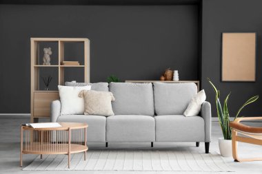 Gri kanepesi, masası ve raf ünitesi olan modern oturma odası.