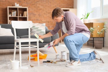 Boyalı paletleri ve sandalyesi olan genç bir adam.