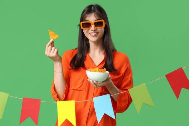 Nachos ve yeşil arka planda renkli kiraz çiçekleri olan genç bir kadın. Cinco de Mayo kutlaması