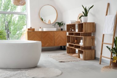 İçinde seramik küvet ve bitkiler olan hafif bir banyo.