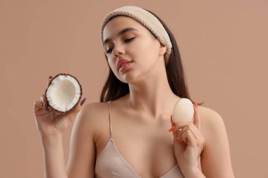 Bej arka planda sabun ve hindistan cevizi olan bantlı genç kadın, yakın plan.