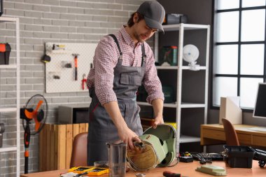 Atölyedeki masada kahve makinesini tamir eden erkek işçi.