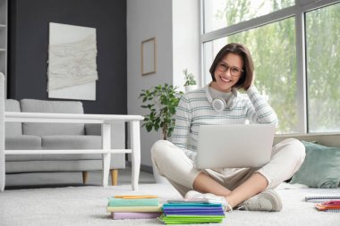 Güzel öğrenci evde dizüstü bilgisayarla ders çalışıyor.