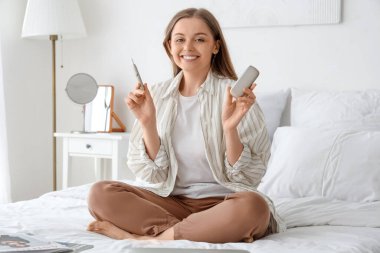 Evdeki yatakta elektronik puro içen genç bir kadın.