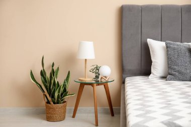 Yatak odasındaki rahat yatağın yanında lamba olan komodin.