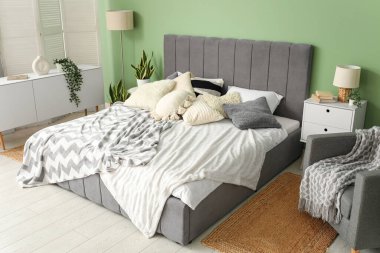 Yatağı, komodinleri, koltuğu ve lambası olan modern yatak odası.