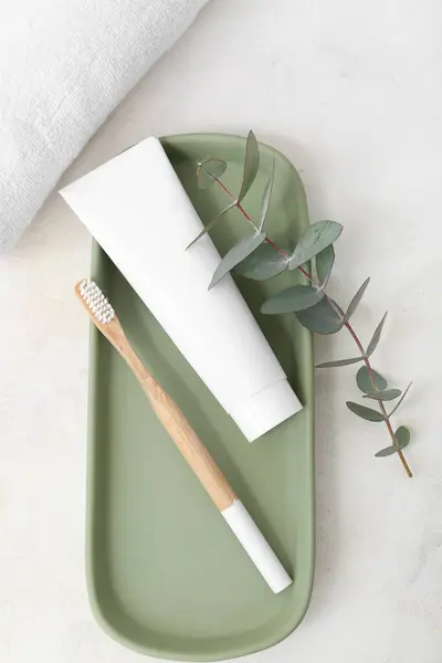 Teller Mit Bambuszahnbürste Paste Und Eukalyptuszweig Auf Hellem Hintergrund Stockfoto