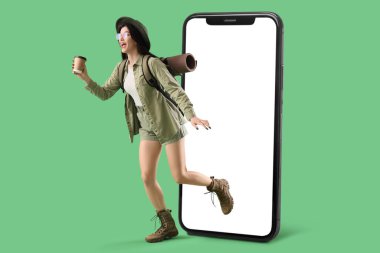 Happy female tourist and big smartphone on green background