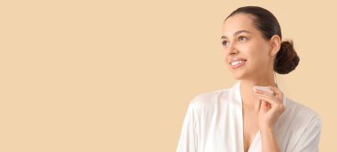 Beautiful young woman massaging her neck with guasha on beige background with space for text