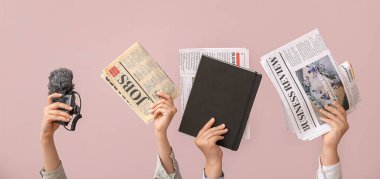 Hands with newspapers, microphone and notebook on pink background