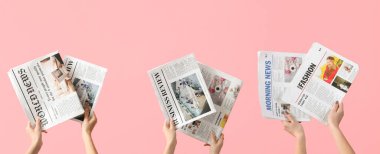 Hands with newspapers on pink background