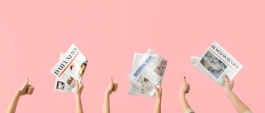 Hands with newspapers showing thumb-up on pink background