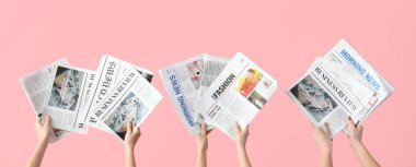 Hands with newspapers on pink background