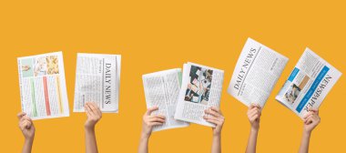 Hands with newspapers on yellow background
