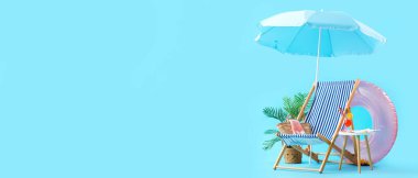 Deck chair, umbrella and beach accessories on blue background with space for text