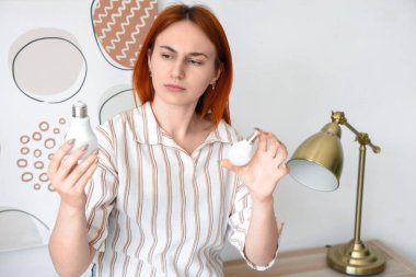 Evde ampulleri seçen düşünceli genç bir kadın.